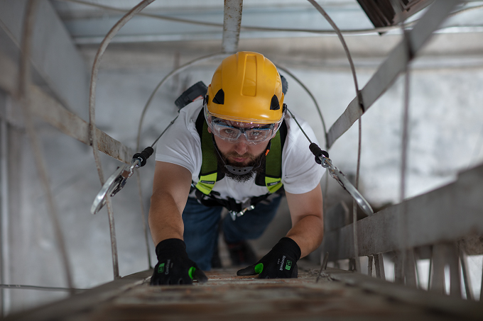 Man working at height wearing a yellow helmet in a harness