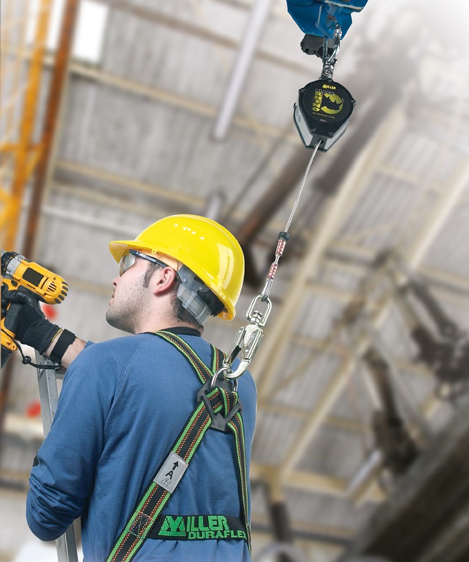 man working at height wearing a harness, yellow helmet and drill in hand