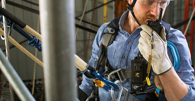 Man talking on a radio wearing fall protection 