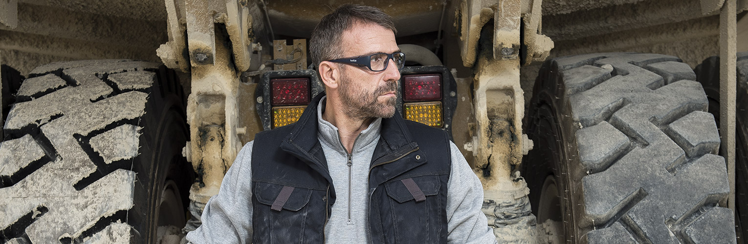 Man wearing safety glasses next to large wheels