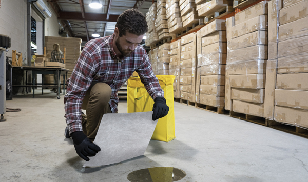 A man cleaning an oil spill with a pad 